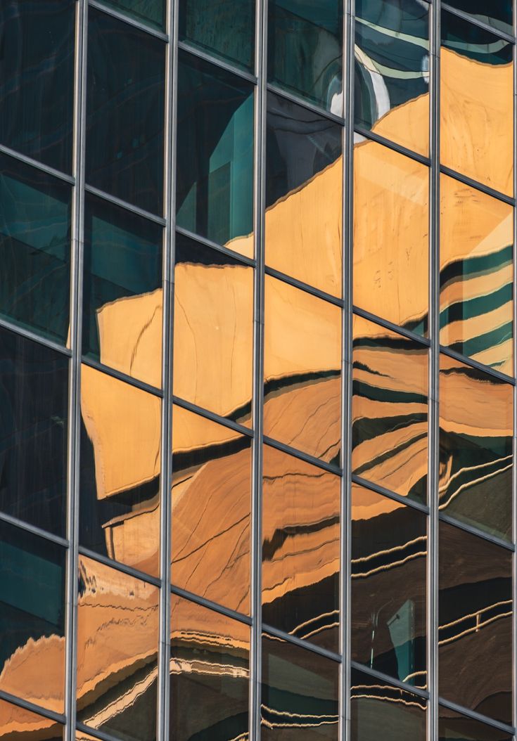 Glass facade reflecting golden cliff-like forms